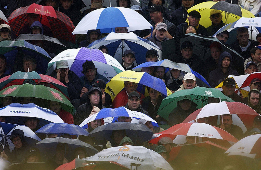 Spectators take cover under umbrellas during a storm at Muirfield in 2002